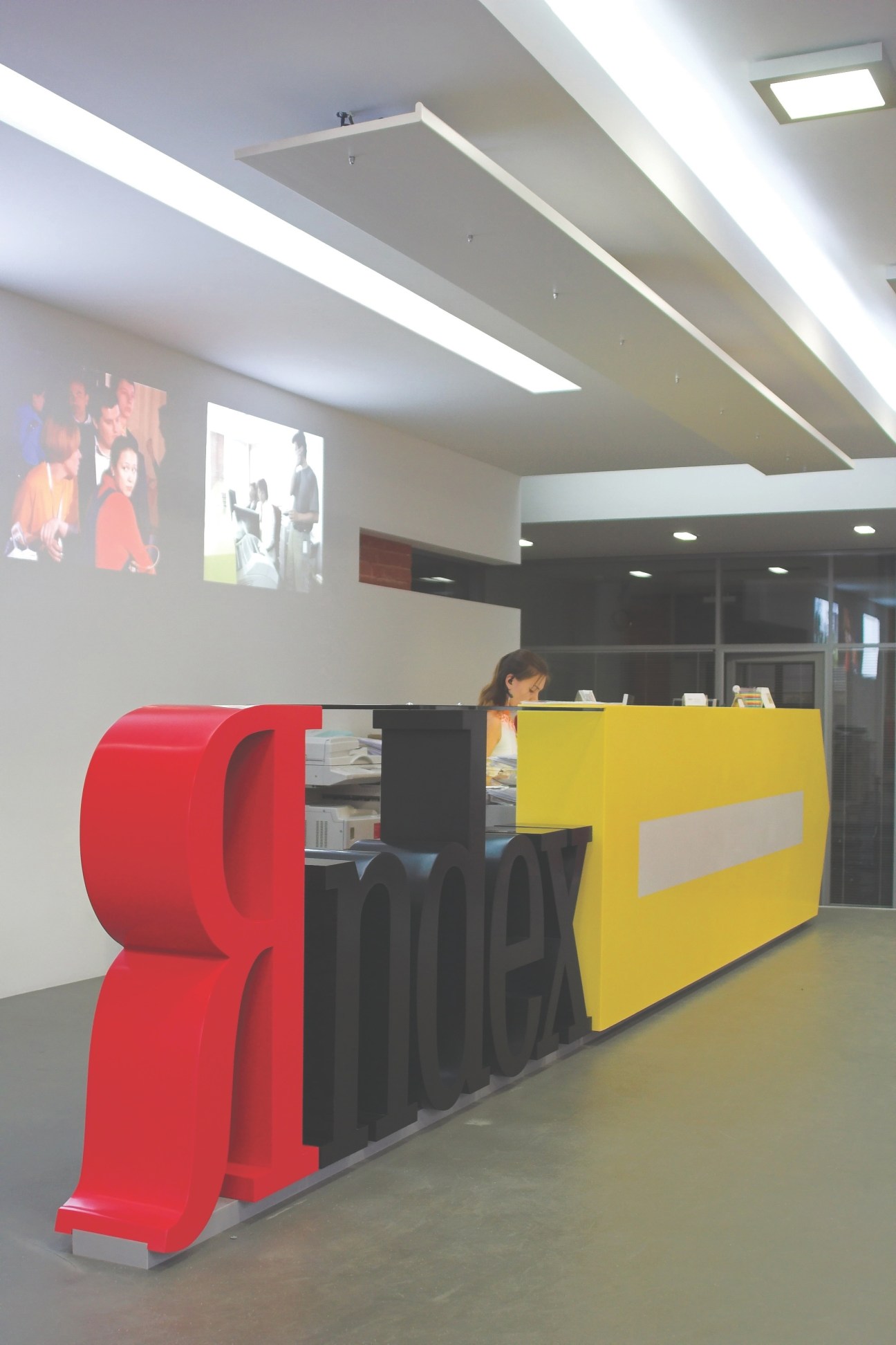 Modern office reception desk with red and yellow geometric panels and Yandex branding on wall.