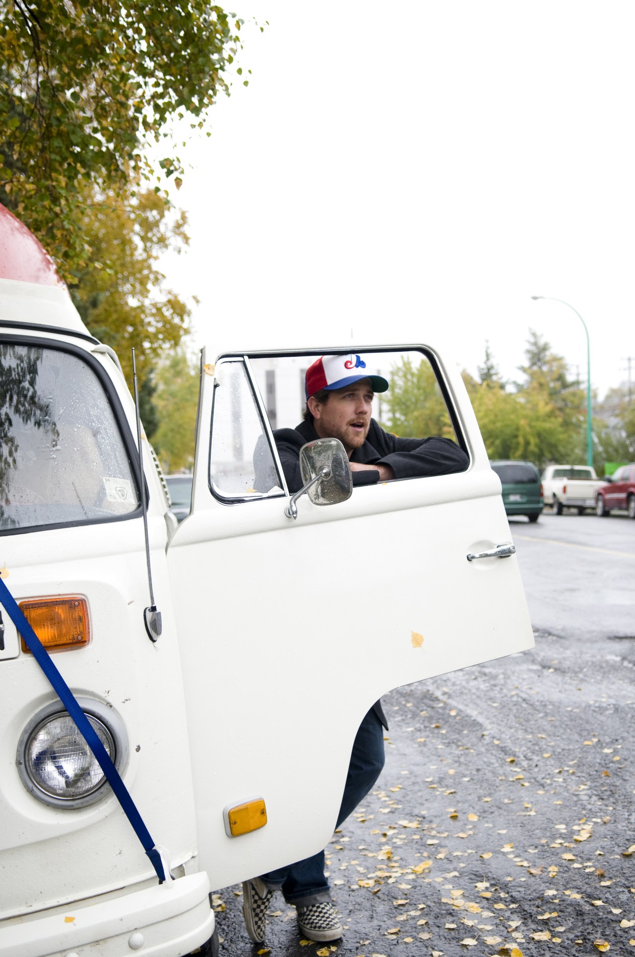 CBC reporter Loren McGinnis sits in the cab of a white truck wearing a red and blue cap.
