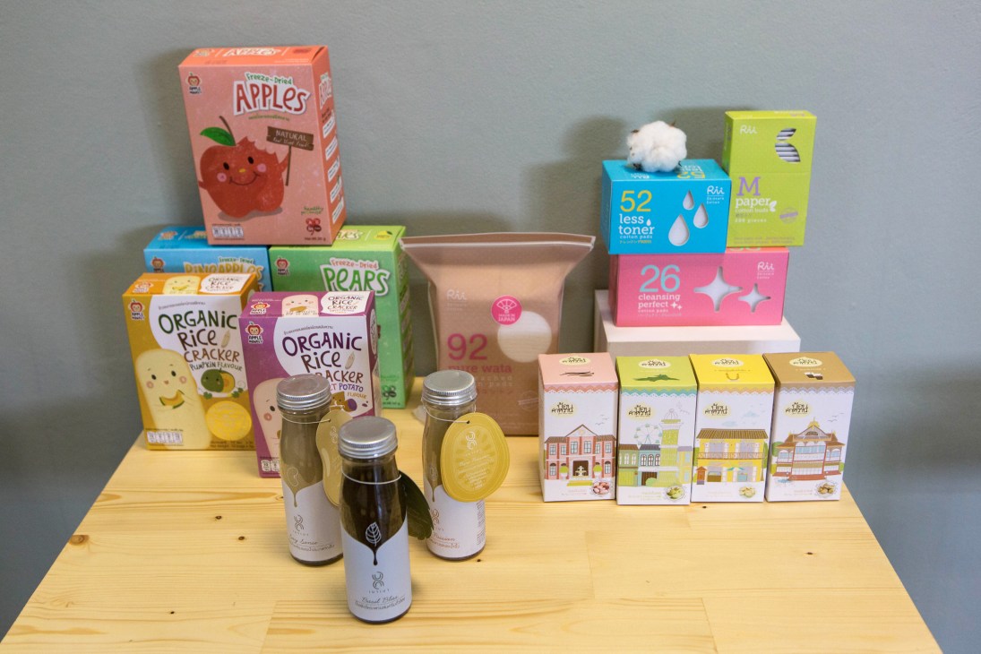 Various colorful product packages and bottles arranged on wooden surface including cereal boxes and skincare items