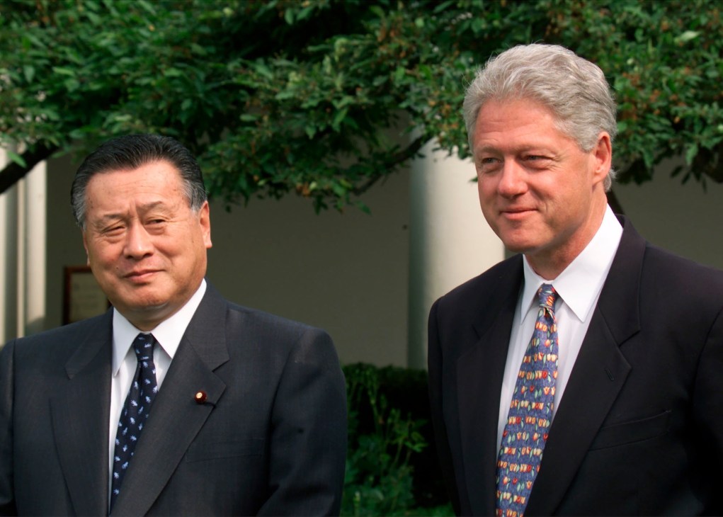 Yoshio Mori in a dark suit standing next to Bill Clinton outdoors.
