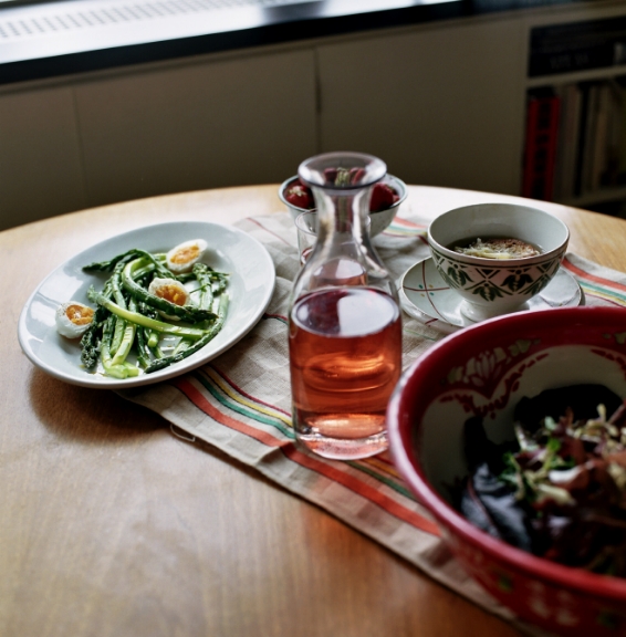 A table setting with asparagus and eggs, soup, and a carafe of rosé wine.