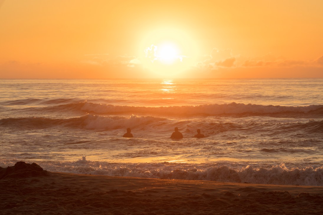 Silhouetted swimmers in the Atlantic Ocean at sunset in Punta del Este, Uruguay.