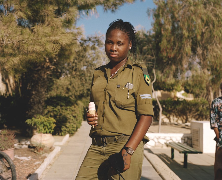 Rayahnah Jackson, 19, in Israeli army uniform holding ice cream among cypress trees