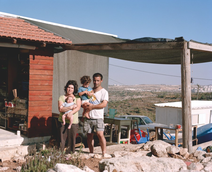 The Miar family stands outside a modest home on the unauthorised Jewish settlement of Sde Boaz in the West Bank, holding their young children.