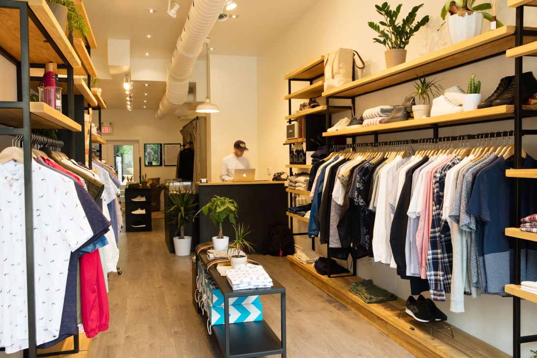 Modern clothing store interior with wood shelving displaying men's shirts and casual wear